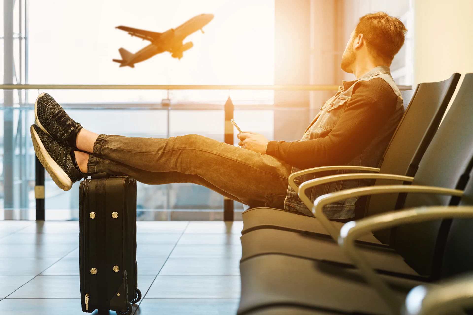 Viajante descansando no saguão do aeroporto enquanto um avião decola